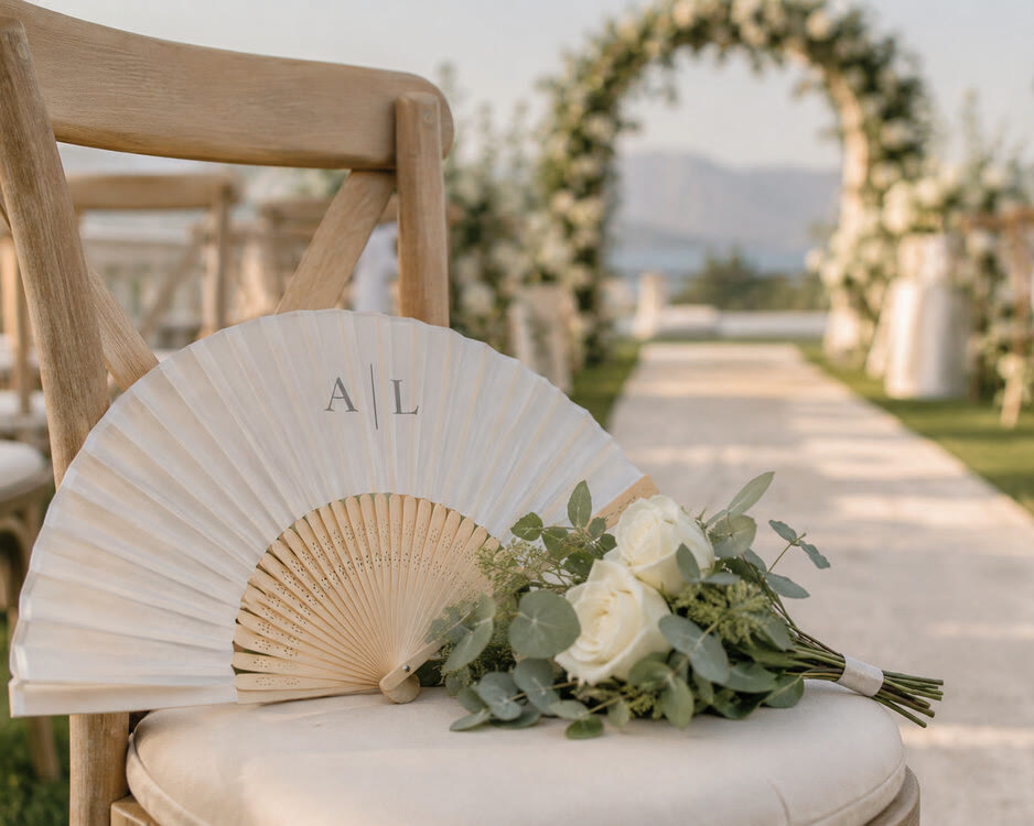 Ventaglio bianco in bambù con monogramma stampato su una sedia da cerimonia